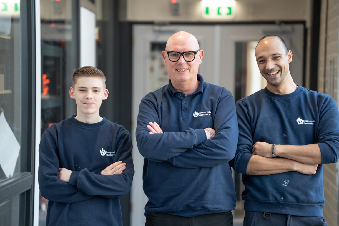 Drie collega's van een leerwerkorganisatie naast elkaar in de werkplaats.